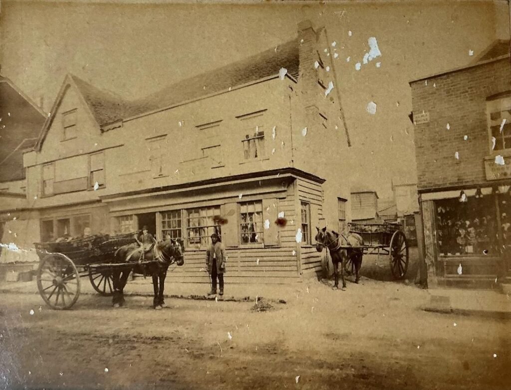 An early photograph of Ongar, dated around 1870 showing 134 High Street, currently occupied by Balgores Hayes, Estate Agents.
The property on the right has a sign ‘Alma House.’ and is currently occupied by Capital Flowers.