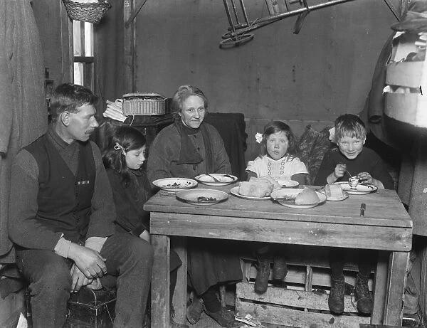 The family sitting round their table. The father is seen wearing his medal ribbons.