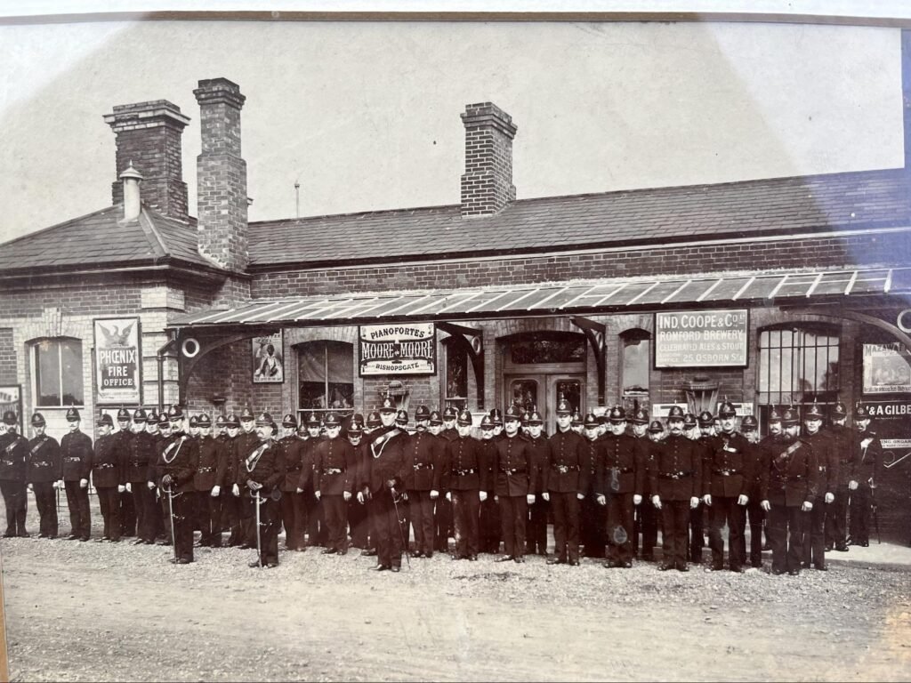 The picture above shows the Ongar Rifle Volunteers (circa 1880?) parading outside we believe Ongar Railway Station. We do not know what the occasion was, but it is possibly when Queen Victoria visited Essex during her Jubilee.
The 18th Volunteer Rifles were formed in 1860. Captain Budworth was the first commanding officer. The total strength as reported in the Essex Almanac of 1864 was 59.
Although the location is thought to be Ongar Railway Station there is some doubt as the architecture to the left of the building is different to how it is currently. There appears to be no record of any changes to the building and so further research is needed.